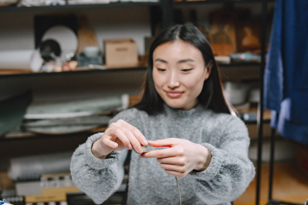 A focused young woman sewing in a craft workshop, symbolizing creativity and small business.