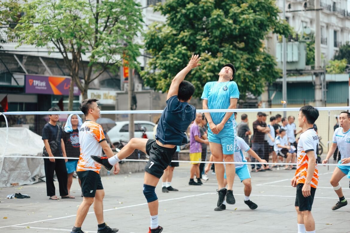 Men playing an intense volleyball game outdoors in a bustling urban area.